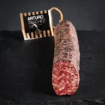 Salchichón Bellota Arturo Sánchez u komadu, s vidljivim komadićima mesa i bijele masnoće na presjeku.